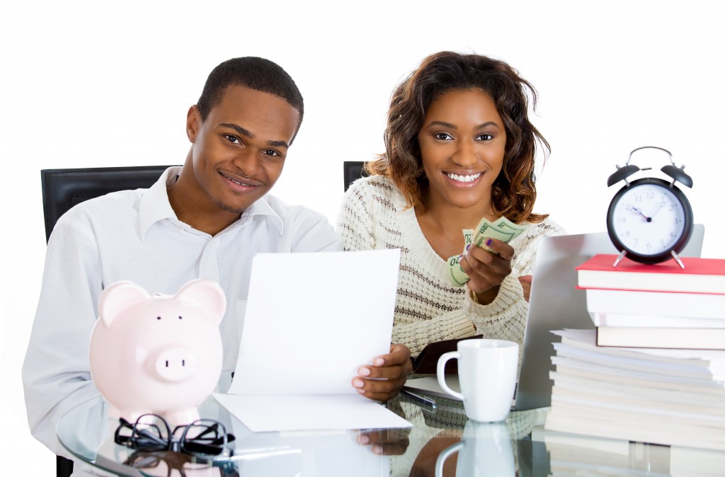 spending-monthly-budget-young-couple-piggy-bank-clock-papers-table-1024x674.jpg