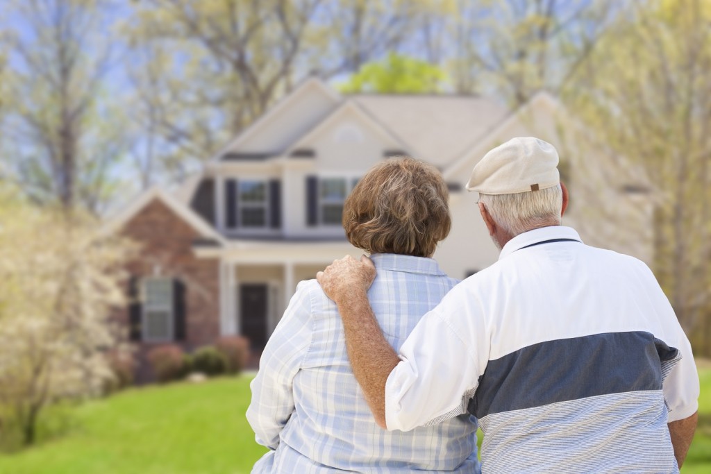Older-couple-in-front-of-house-retired-pensioners-equity-release-property-wealth-re-sized-1024x683.jpg